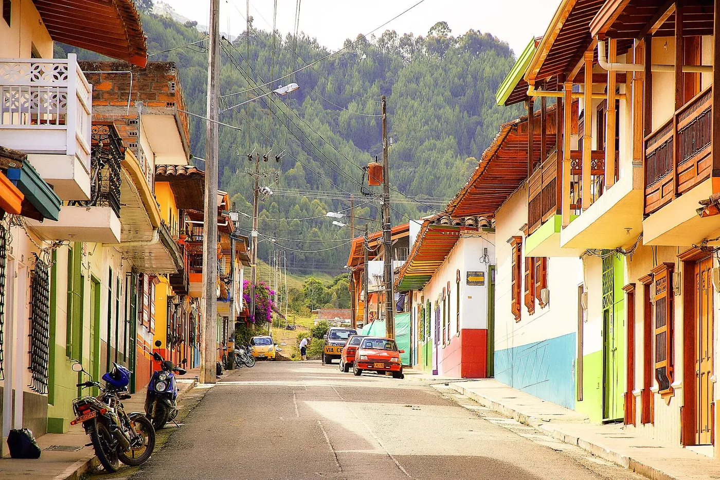 Calle empinada de Jardín con balcones de colores y montaña al fondo