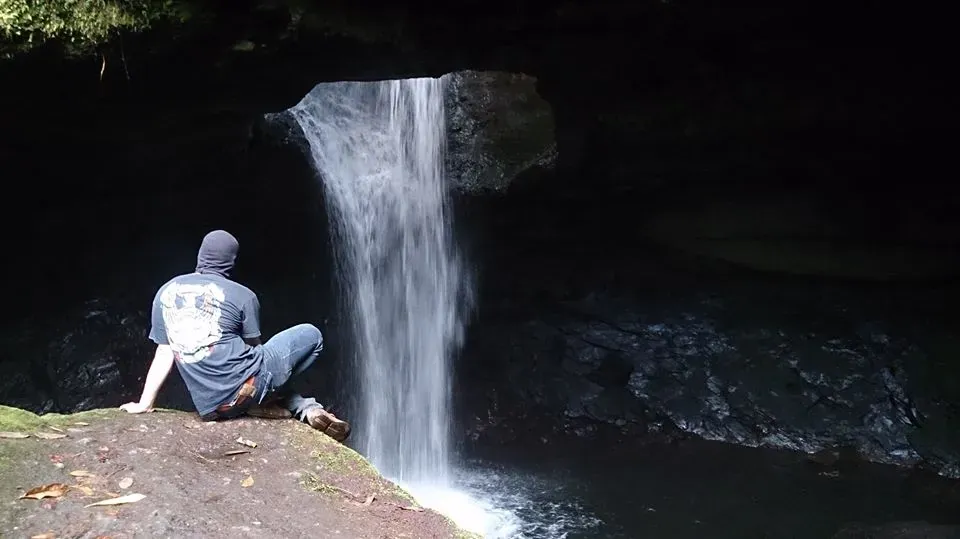 Visitante junto a la caída de agua dentro de la Cueva del Esplendor