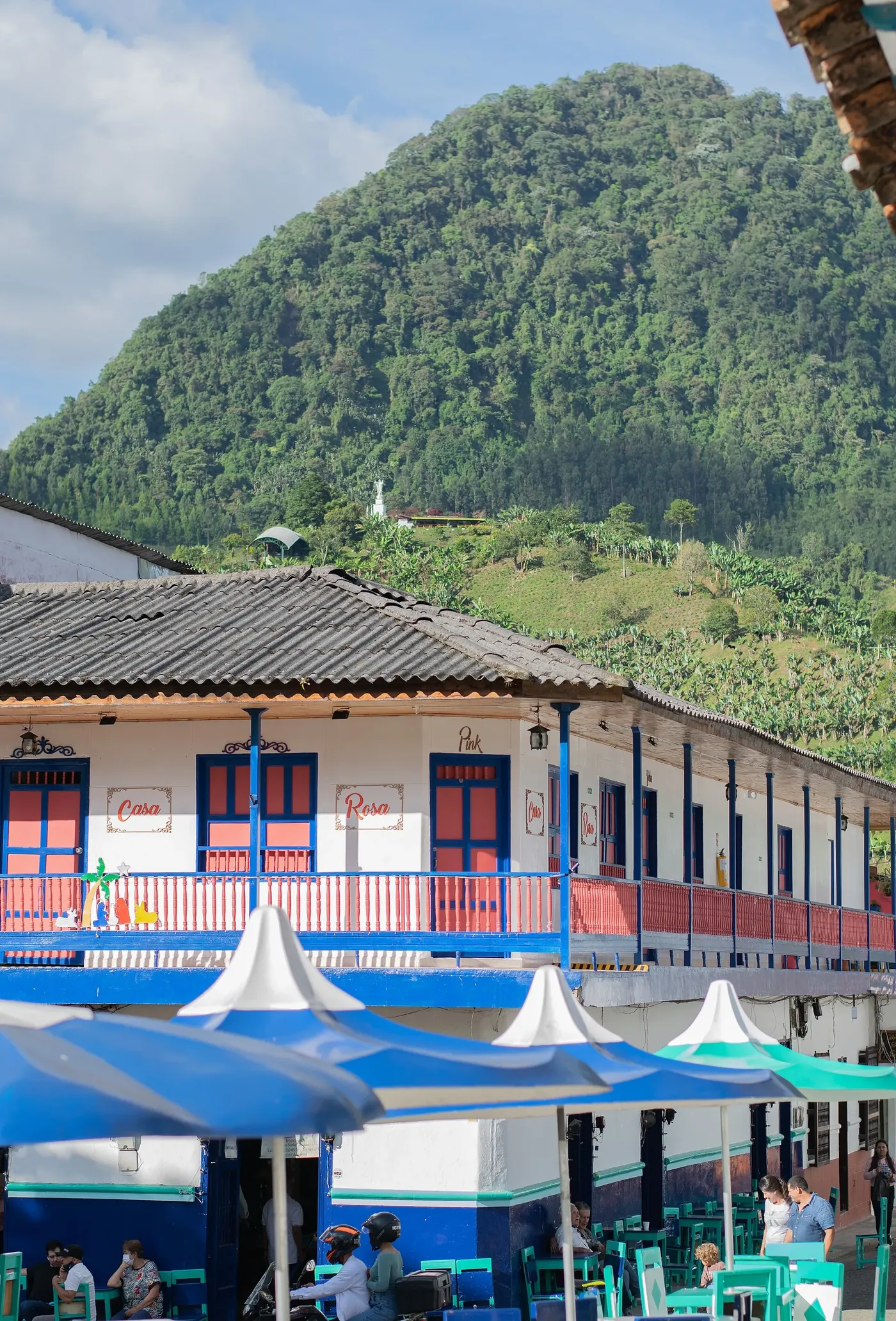 Casa de balcones con montaña boscosa detrás, en Jardín