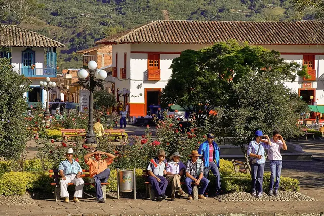 Bancas y árboles del parque principal de Jardín con gente conversando