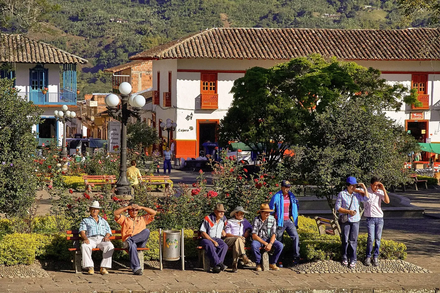 Bancas y árboles del parque principal de Jardín con gente conversando